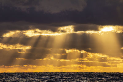 Scenic view of sea against dramatic sky during sunset