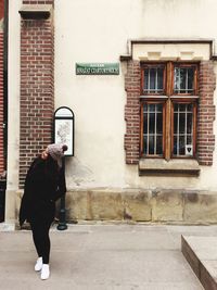 Full length of woman standing against built structure