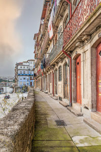 Empty footpath amidst buildings in city