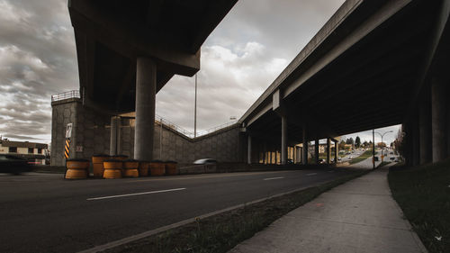 Road by bridge in city against sky