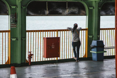 Full length rear view of woman standing on boat in sea