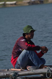 Side view of man sitting on pool raft in lake