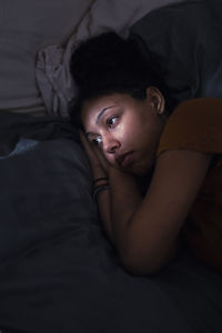 Pensive young woman lying in bed