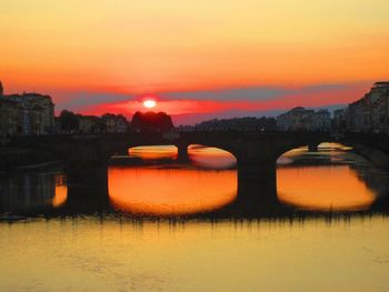 View of illuminated bridge over river at sunset