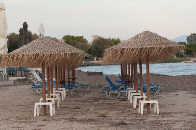 Deck chairs on beach against sky