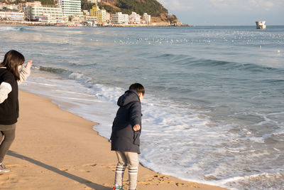 Rear view of friends standing on beach