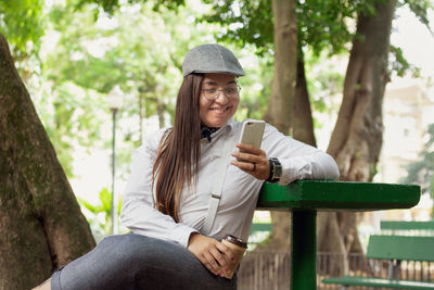 Young woman using phone while sitting on bench