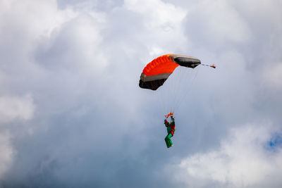 Low angle view of person paragliding against sky