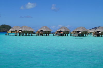 Stilt houses over sea against sky