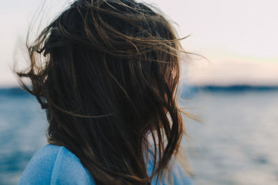 Rear view of woman at beach against sky