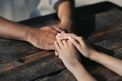 Cropped hands of couple holding hands on table