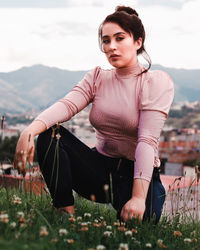 Young woman with arms raised on field against sky