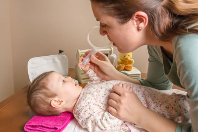 Side view of cute girl holding baby