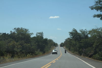 Car on road amidst trees against sky