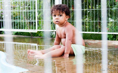 Portrait of cute boy sitting at swimming pool