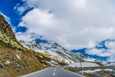 Road amidst snowcapped mountains against sky