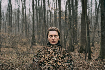 Woman with mirror against bare trees in forest