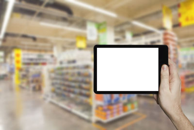 Close-up of woman holding digital tablet with blank screen in supermarket