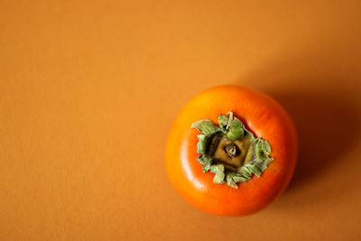 Close-up of persimmon against orange background