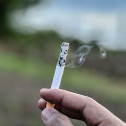 Close-up of hand holding cigarette