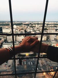 Close-up of holding hands with cityscape in background