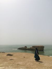 Side view of woman walking on shore against sea at beach