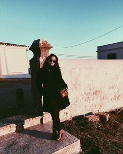 Portrait of young woman standing on wall