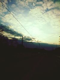 Electricity pylon against cloudy sky