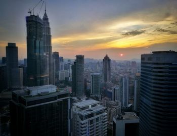 Skyscrapers in city at sunset