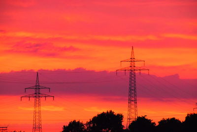 Low angle view of silhouette electricity pylon against romantic sky