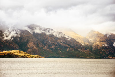 Scenic view of mountains and lake against cloudy sky