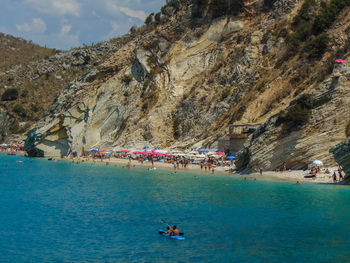 People on boat in sea against mountain