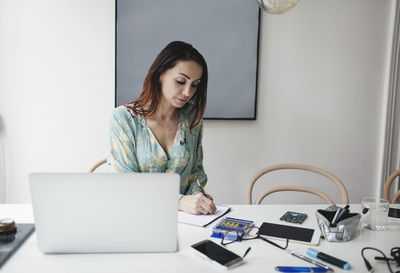 Businesswoman working at table in home office