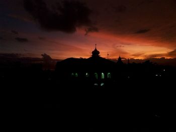 Silhouette built structure against orange sky