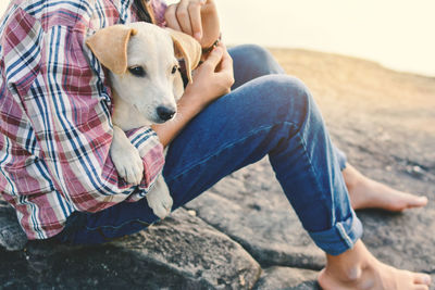 Low section of woman with dog sitting outdoors