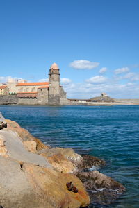 View of building by sea against blue sky