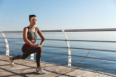 Woman exercising against clear blue sky