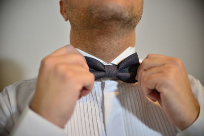 Midsection of man adjusting bow tie