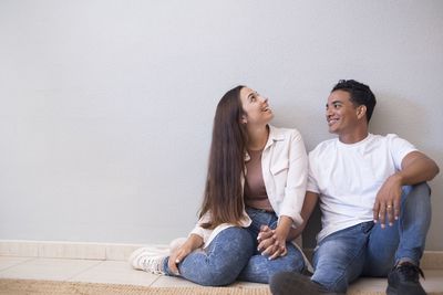 Young couple sitting against wall