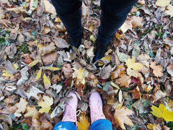 Low section of people standing on fallen leaves