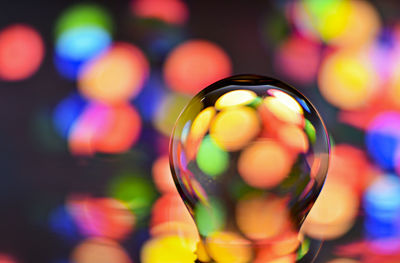 Close-up of glass ball against defocused illuminated background