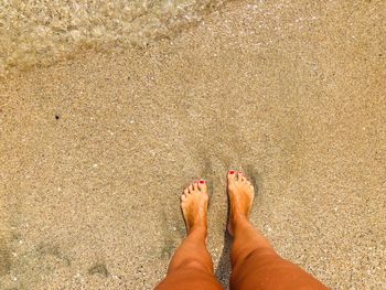 Low section of woman standing at sandy beach