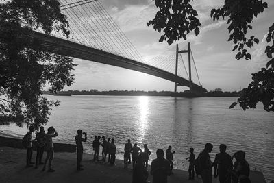 People on bridge over river against sky