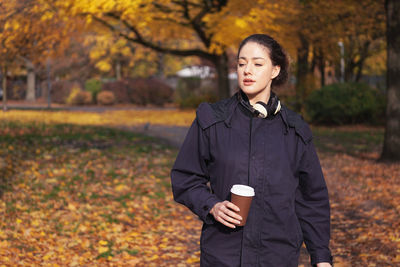 Young woman wearing jacket standing at park during autumn