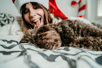 Laughing woman relaxing with dog on bed at home