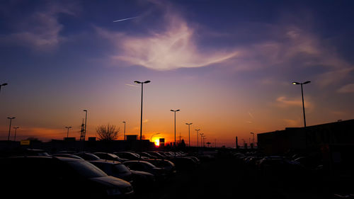 Cars on street against sky at sunset