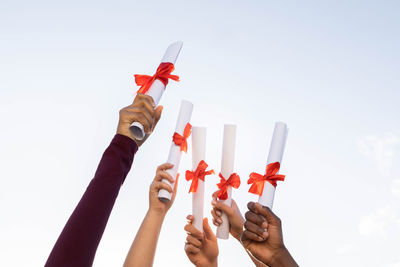 Cropped hand of woman holding gift against white background