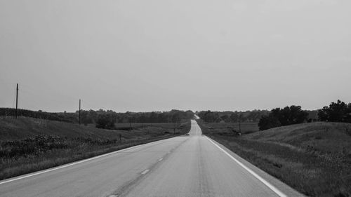 Road amidst field against clear sky