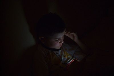 Close-up of boy using smart phone in darkroom