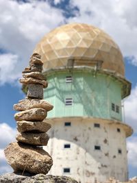 Low angle view of stone stack on rock against sky